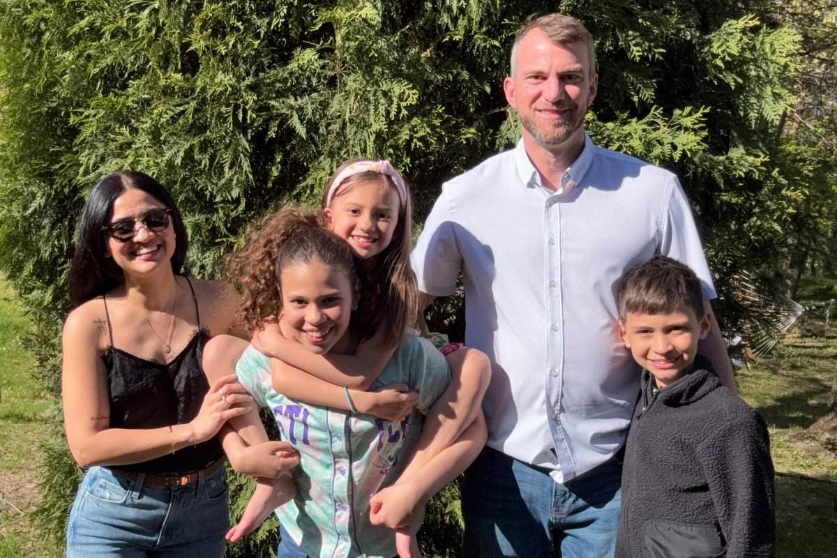 Andrew Malm with his wife and three kids in front of an evergreen tree